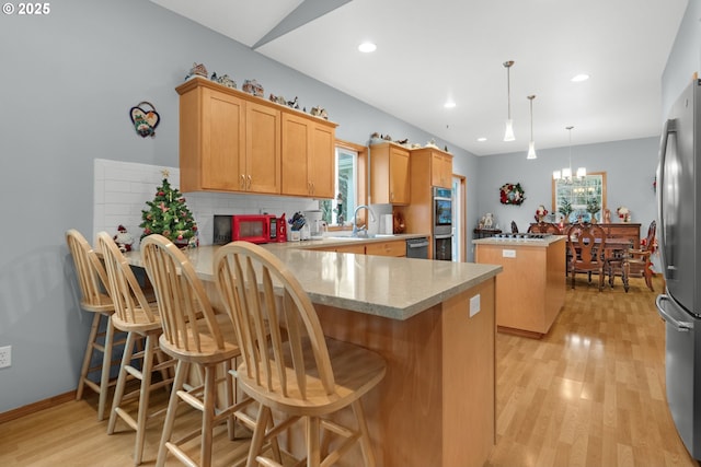 kitchen featuring a breakfast bar area, kitchen peninsula, a wealth of natural light, and hanging light fixtures