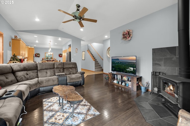 living room with a wood stove, ceiling fan, dark wood-type flooring, and vaulted ceiling