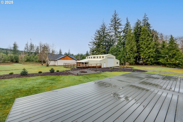 wooden deck featuring an outbuilding, a garage, and a lawn