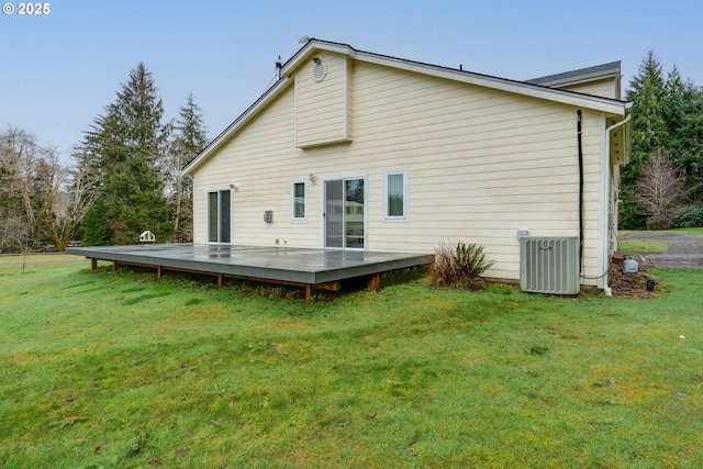 rear view of house featuring cooling unit, a wooden deck, and a lawn