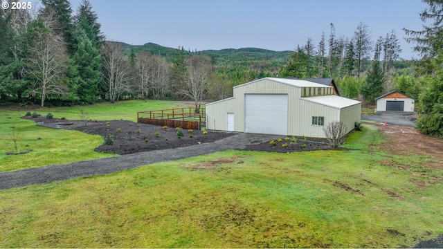 view of outdoor structure with a lawn, a mountain view, and a garage