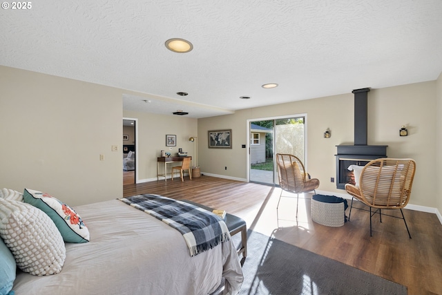 9080 SW Brier Ln, Portland, OR 97223 - bedroom with wood finished floors, access to exterior, a wood stove, baseboards, and a textured ceiling