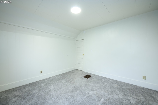 carpeted spare room with lofted ceiling