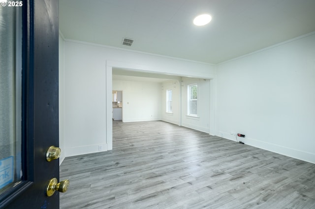 empty room featuring light hardwood / wood-style flooring and crown molding