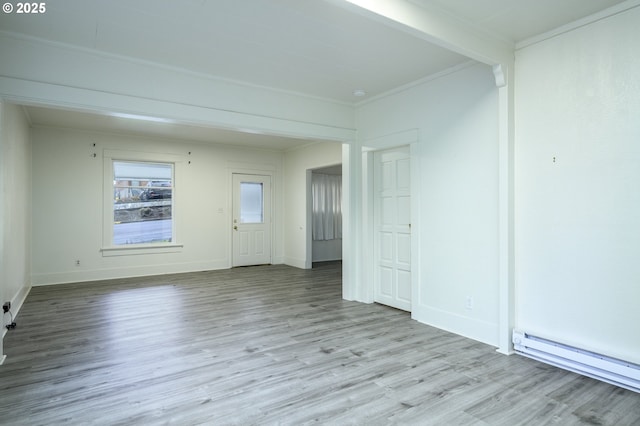 empty room featuring crown molding, light wood-type flooring, and a baseboard heating unit