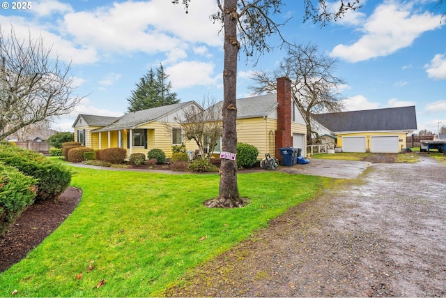 view of front of home featuring driveway, a chimney, and a front lawn