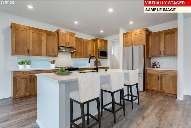3839 S Arwana Ln, Ridgefield, WA 98642 - kitchen featuring freestanding refrigerator, light countertops, stainless steel microwave, under cabinet range hood, and a sink