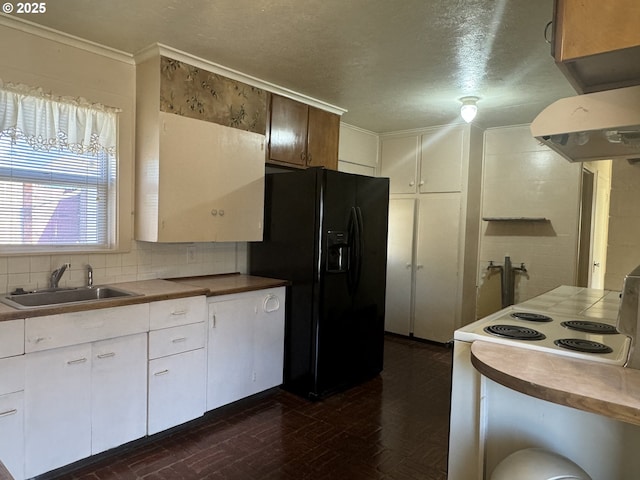 kitchen featuring electric range, a sink, white cabinets, black fridge, and backsplash