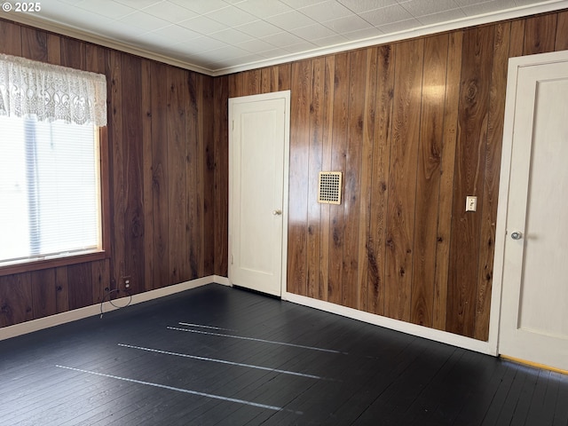 spare room featuring dark wood-style flooring, visible vents, and baseboards