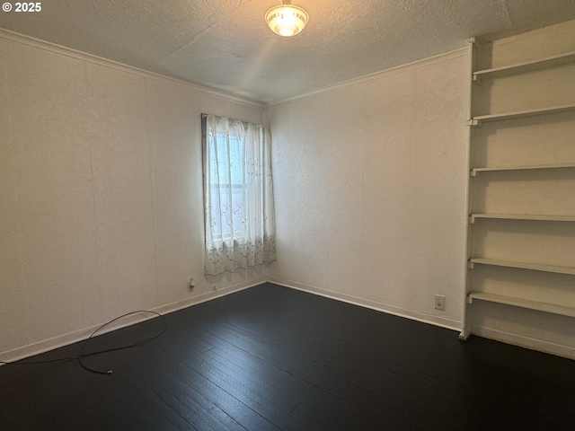 spare room with dark wood-style flooring, a textured ceiling, and baseboards