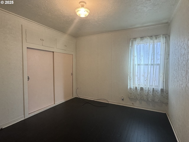 unfurnished bedroom with a textured ceiling, a closet, wood-type flooring, and baseboards