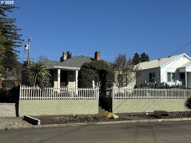 view of front facade with covered porch and a fenced front yard