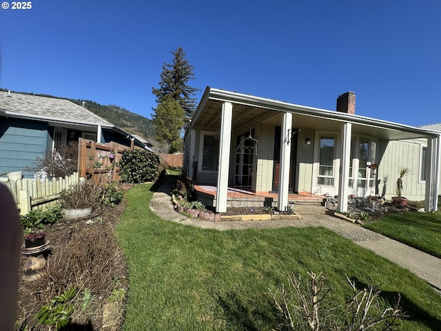 view of home's exterior with a chimney, fence, and a lawn