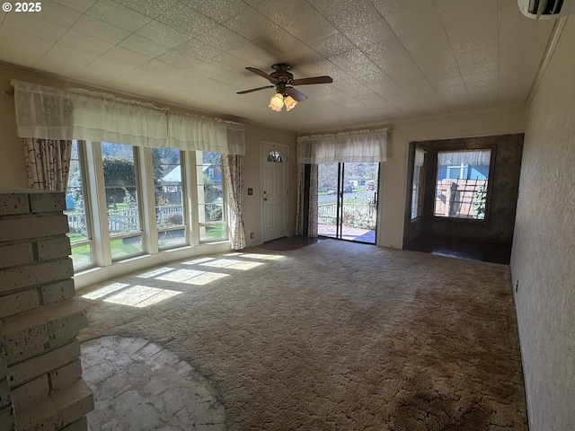 unfurnished living room featuring carpet floors, ornamental molding, and a ceiling fan