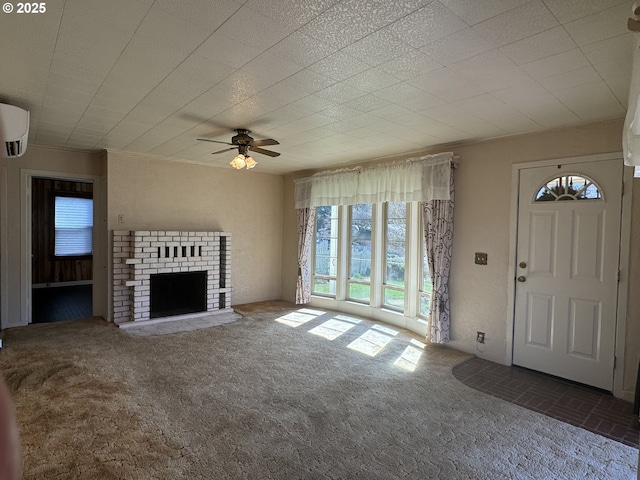 unfurnished living room with a wall mounted AC, ornamental molding, a ceiling fan, a brick fireplace, and carpet flooring