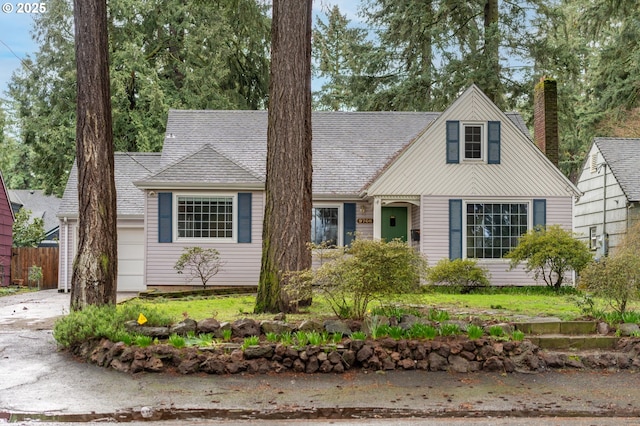 view of front of house with concrete driveway, fence, and a shingled roof