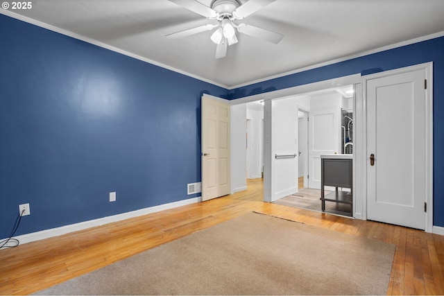 unfurnished bedroom featuring visible vents, hardwood / wood-style floors, crown molding, baseboards, and ceiling fan