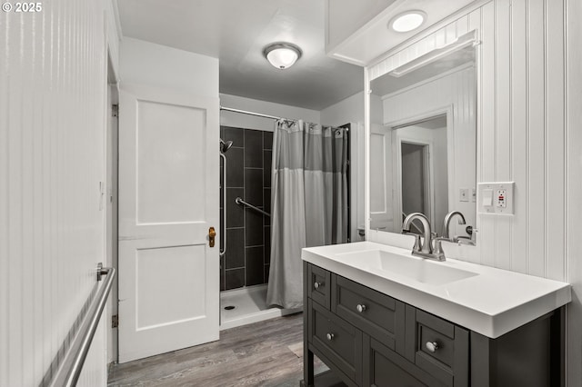 full bath featuring wood finished floors, vanity, and a tile shower