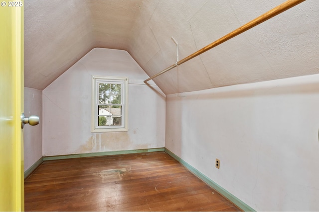 additional living space featuring lofted ceiling, baseboards, wood-type flooring, and a textured ceiling