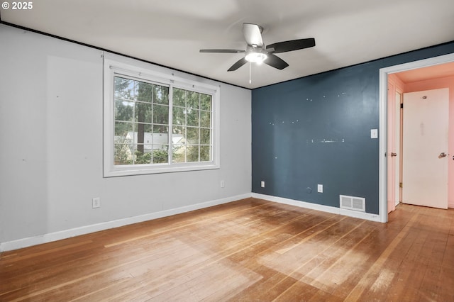 empty room featuring visible vents, baseboards, a ceiling fan, and hardwood / wood-style flooring