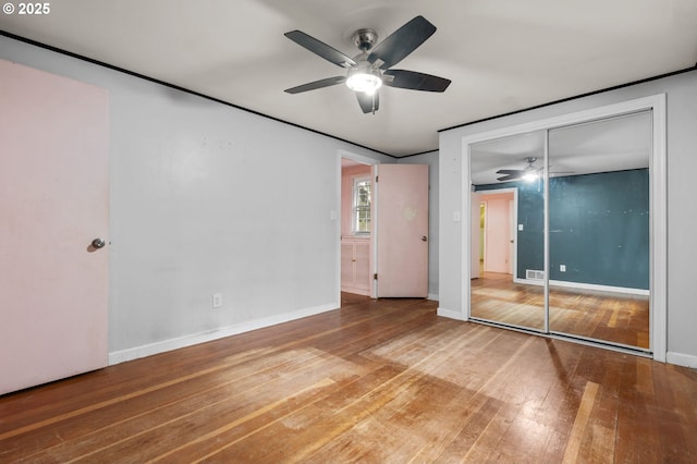 unfurnished bedroom featuring visible vents, hardwood / wood-style floors, a closet, baseboards, and ceiling fan