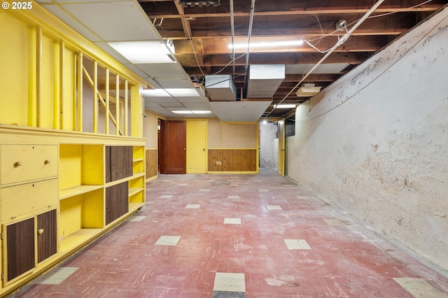 unfinished below grade area with tile patterned floors and a wainscoted wall