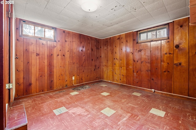 below grade area featuring tile patterned floors, wooden walls, and baseboards