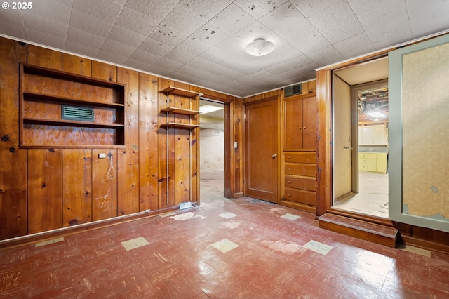 unfurnished bedroom featuring wooden walls and visible vents