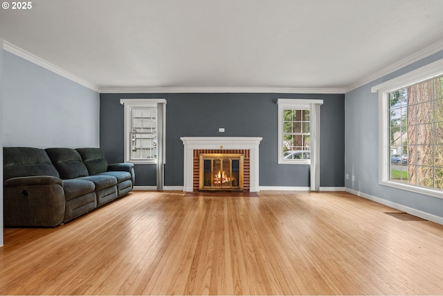 living area with crown molding, light wood-style floors, baseboards, and visible vents