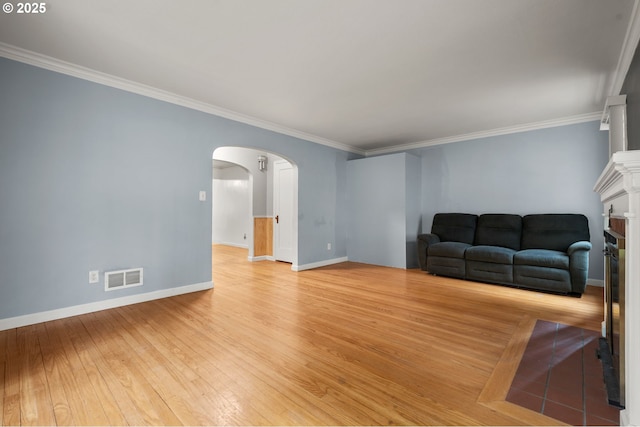 living room with visible vents, ornamental molding, arched walkways, light wood-style floors, and baseboards