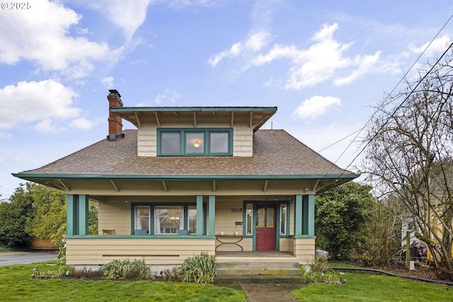 view of front facade featuring covered porch, a front lawn, a chimney, and a shingled roof