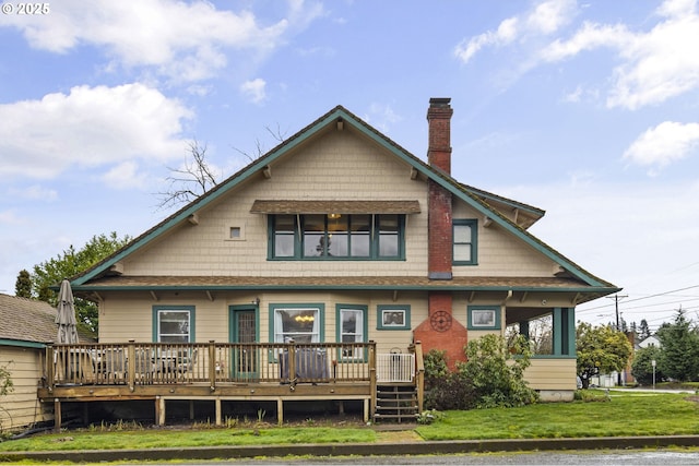 rear view of property with a deck, a yard, and a chimney