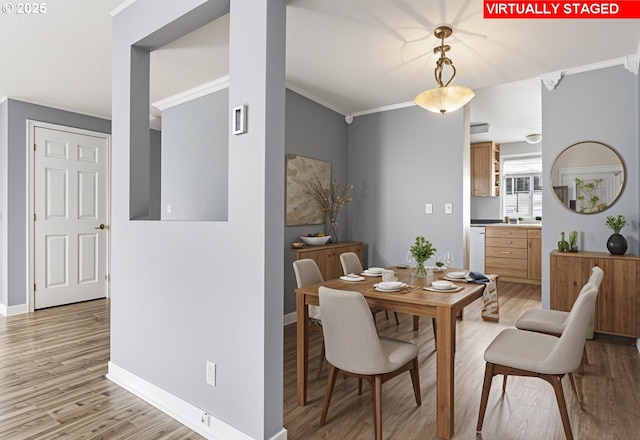 dining space featuring light wood finished floors, baseboards, and crown molding