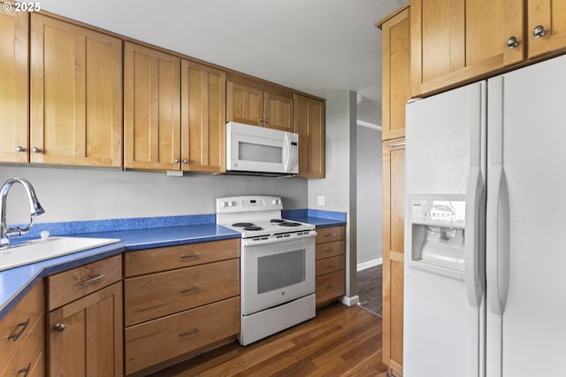 kitchen featuring a sink, brown cabinetry, white appliances, and dark wood-style flooring