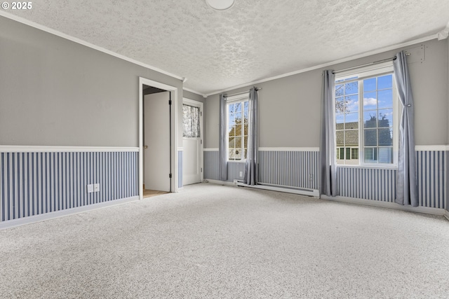 spare room with ornamental molding, a wealth of natural light, wainscoting, and a textured ceiling