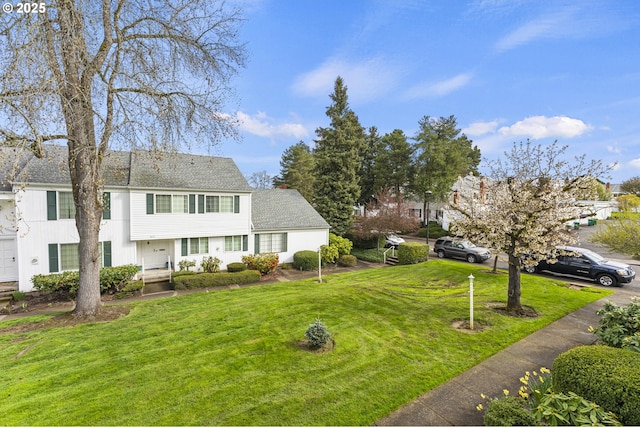 view of front facade featuring a shingled roof and a front lawn