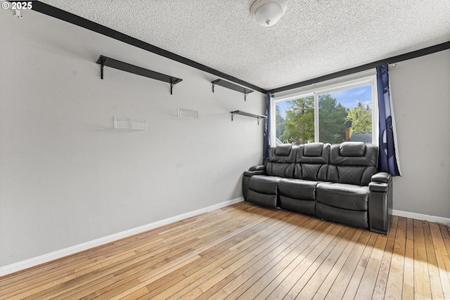 living area with hardwood / wood-style floors, baseboards, and a textured ceiling