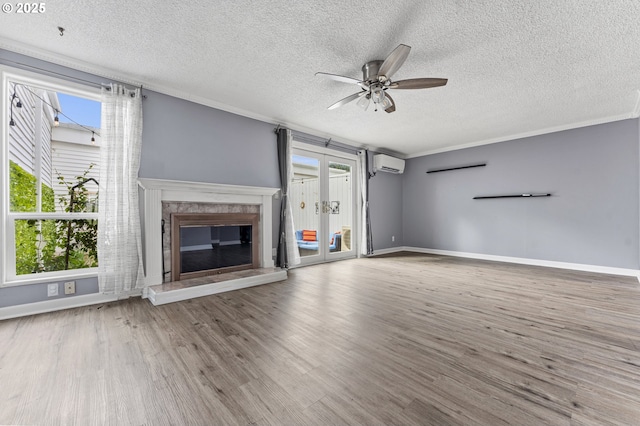 unfurnished living room featuring a wall mounted air conditioner, a ceiling fan, crown molding, and wood finished floors