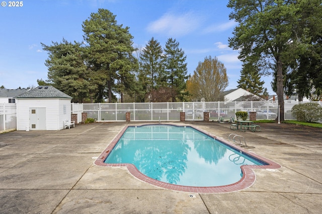 pool featuring an outbuilding, a patio area, and fence
