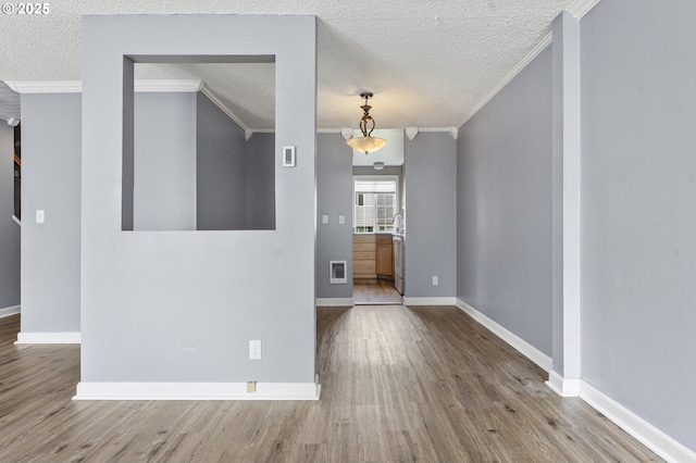 spare room with ornamental molding, baseboards, and wood finished floors