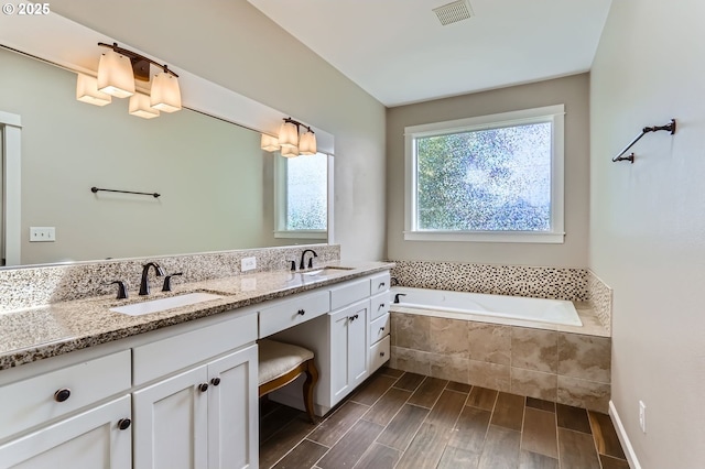 full bathroom with a garden tub, double vanity, and wood finished floors