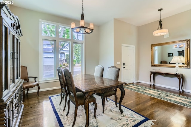 dining room featuring dark wood-style flooring, a chandelier, healthy amount of natural light, and baseboards