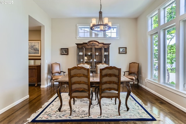 dining room with a chandelier, baseboards, and dark wood-style floors