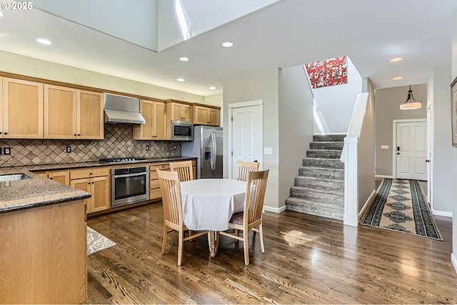 kitchen with stainless steel appliances, wall chimney range hood, decorative backsplash, dark wood-style floors, and recessed lighting
