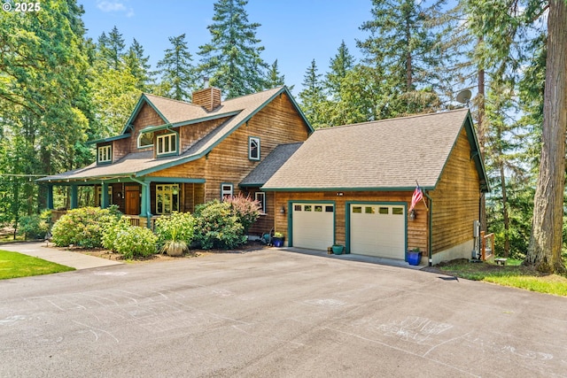 770 N Moss St, Lowell, OR 97452 - view of front of house featuring an attached garage, roof with shingles, a chimney, asphalt driveway, and covered porch