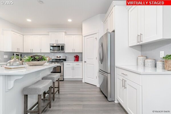 2747 Woodfern Ter Lot 57, Eugene, OR 97403 - kitchen with appliances with stainless steel finishes, a breakfast bar area, white cabinetry, light countertops, and recessed lighting