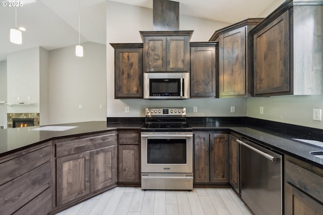 kitchen with stainless steel appliances, dark brown cabinets, dark stone countertops, light wood-type flooring, and hanging light fixtures
