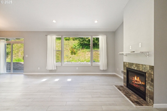 unfurnished living room featuring plenty of natural light, a fireplace, baseboards, and recessed lighting