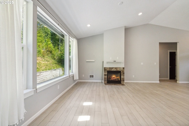 unfurnished living room featuring vaulted ceiling, a high end fireplace, light wood-style flooring, and baseboards