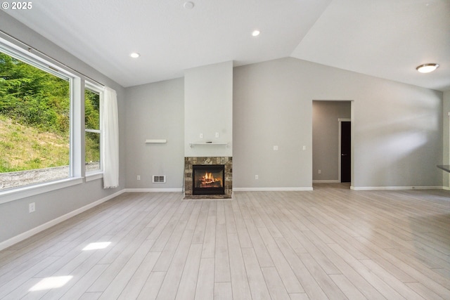 unfurnished living room with vaulted ceiling, light wood finished floors, a fireplace, and baseboards